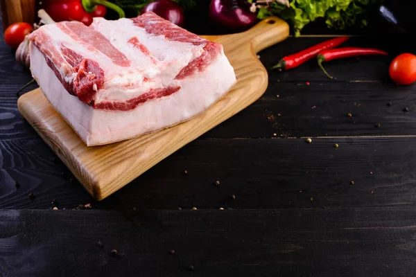raw pork fat against black wooden background for copy space Big piece of fresh fat