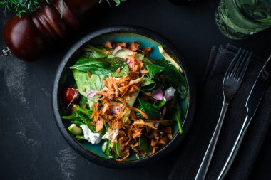 Ispanakla servis edilen gurme salatası, siyah arka planda marul. Lezzetli salata. Sağlıklı yiyecekler. Diyet ve fitness beslenme. Pahalı bir restoranda peynirli taze salata.