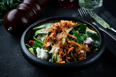 Ispanakla servis edilen gurme salatası, siyah arka planda marul. Lezzetli salata. Sağlıklı yiyecekler. Diyet ve fitness beslenme. Pahalı bir restoranda peynirli taze salata.