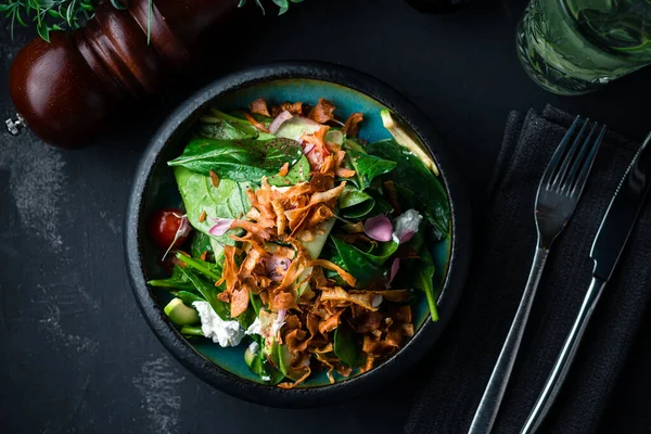Ispanakla servis edilen gurme salatası, siyah arka planda marul. Lezzetli salata. Sağlıklı yiyecekler. Diyet ve fitness beslenme. Pahalı bir restoranda peynirli taze salata.