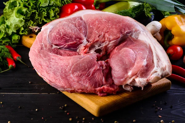 Meat pork fresh. Raw meat on cutting board. raw pork meat part of the hip with fat, Axe and meat pig. Fat piece against black wooden background for copy space