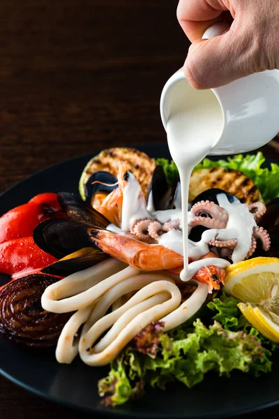 虾仁海鲜中倒入酱汁 龙虾和海鲜的大特写放在盘子里 — 图库照片