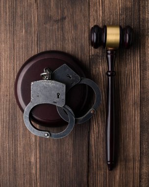 Kelepçe ve yargıç tokmak kahverengi masada, Gavel tahta arka planda duruyor ve kelepçeleniyor kopya alanı için ahşap arka plan