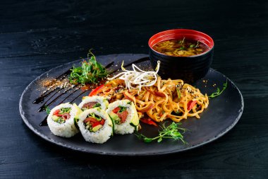 Çeşit çeşit Çin yemeği, erişte, tavuk, rulo, suşi içeren Asya yemekleri masası. Eski ahşap masada servis ediliyor, Asya yemekleri çorba, erişte ve suşi ruloları.