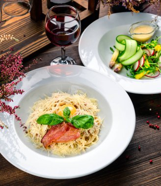 Lezzetli yemek. İtalyan makarnası. Sağlıklı yiyecekler. Kapatın. Pastırmalı, peynirli, turplu ve otlu taze salatalı iki tabak makarna.