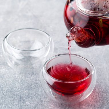 Kırmızı çay çaydanlıktan bir kaseye, ahududu çayı da fotokopi alanı için taze böğürtlenli.