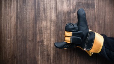 İnşaat eldiveninde işaret parmağı ahşap arka planda.