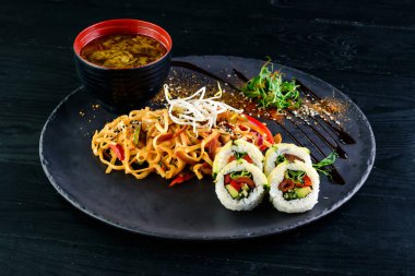 Çeşit çeşit Çin yemeği, erişte, tavuk, rulo, suşi içeren Asya yemekleri masası. Eski ahşap masada servis ediliyor, Asya yemekleri çorba, erişte ve suşi ruloları.