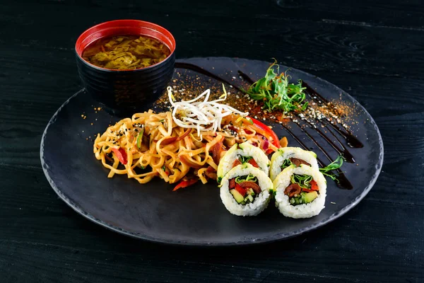 Çeşit çeşit Çin yemeği, erişte, tavuk, rulo, suşi içeren Asya yemekleri masası. Eski ahşap masada servis ediliyor, Asya yemekleri çorba, erişte ve suşi ruloları.