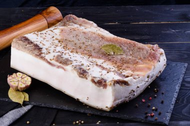 Koyu arkaplanda tuzlanmış pastırma parçaları.