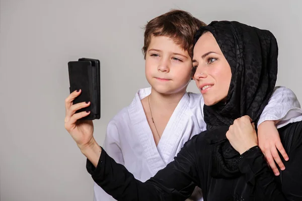 Selfie をしている着物で少し息子と幸せのイスラム教徒ママ — ストック写真