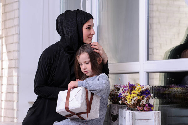 Middle Eastern mother and girl with gift box. Muslim family living lifestyle. Happy smiling Arabic parrent and child.Black and white.