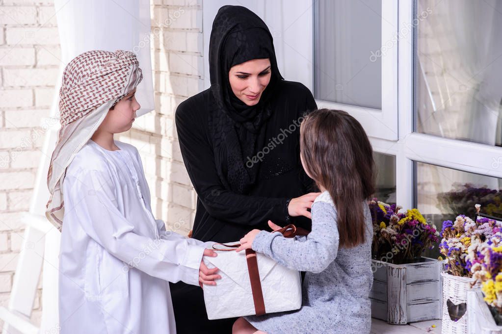 Arabic mother giving gift to her boy and girl.Muslim family.