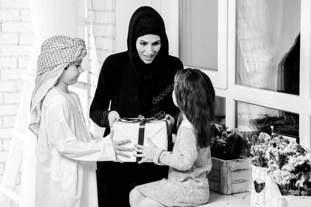 Arabic mother giving gift to her boy and girl.Muslim family.BW
