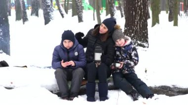 Annemle mutlu iki çocuk kış ormanında çay içiyor. Anneler ve çocukları.