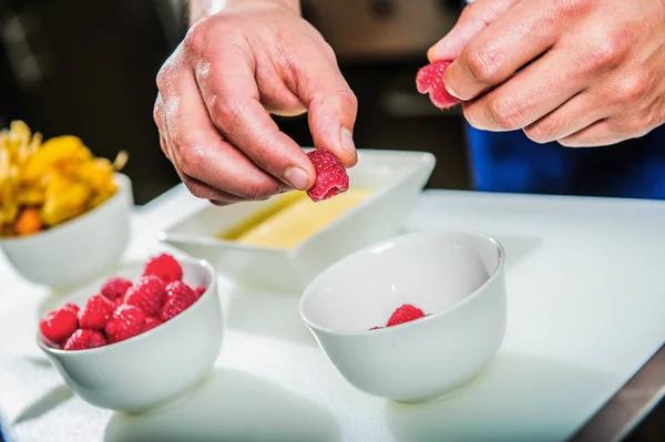 Chef decorating sweets at kitchen. Closeup male chef making dessert in motion. Professional cook decorating cake at workplace.