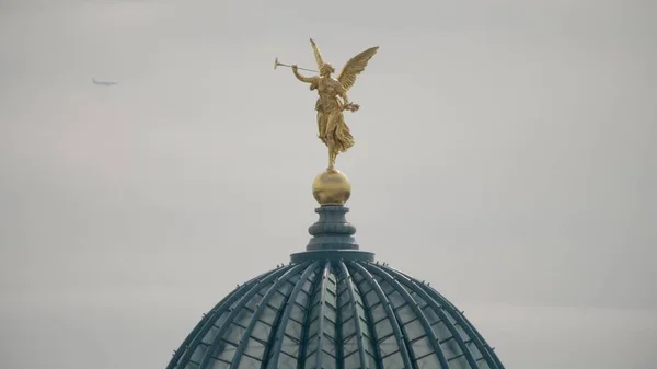 Flygplan som flyger bakom gyllene staty av Pheme eller Fama ovanpå glaskupolen av Dresden Academy of Fine Arts — Stockfoto