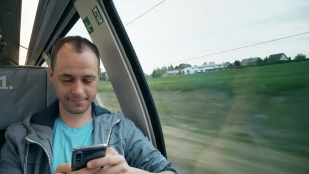 Man SMS op zijn smartphone terwijl het reizen per trein — Stockvideo