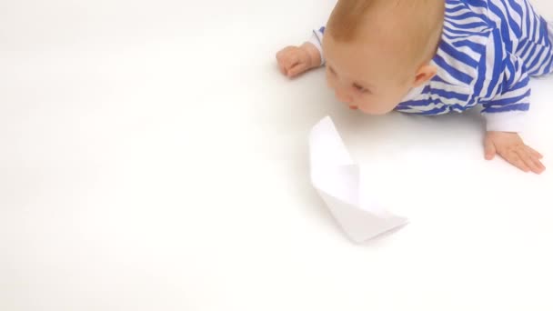 Lindo bebé usando rayas mameluco juega con papel barco — Vídeos de Stock