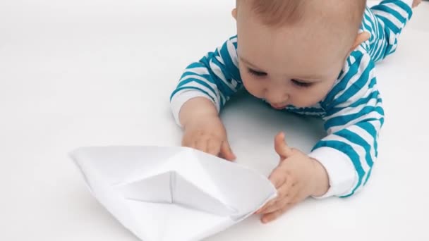 Bebé divertido juega con barco de papel — Vídeos de Stock