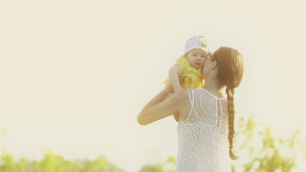 Mother holding her baby girl on summer field in the evening — Stock Video