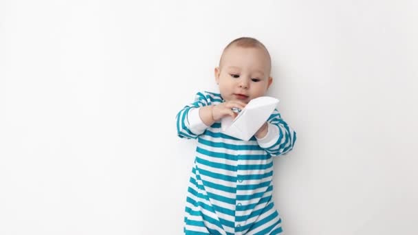 Lachende baby dragen van blauw gestreepte romper speelt met papier boot — Stockvideo