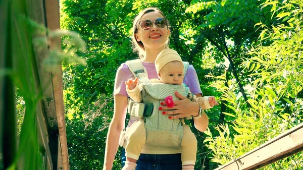 Mulher bonita carregando seu filho em um portador de bebê — Fotografia de Stock