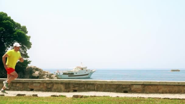 Ευτυχισμένος αρσενικό δρομέας τρέχει στο seaside, αργή κίνηση πυροβολισμό — Αρχείο Βίντεο