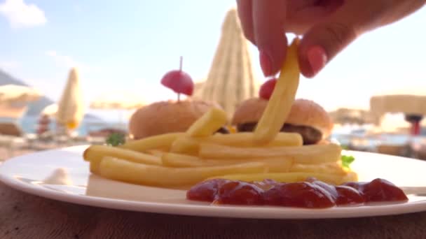 Homem e mulher comendo batatas fritas com ketchup na praia — Vídeo de Stock