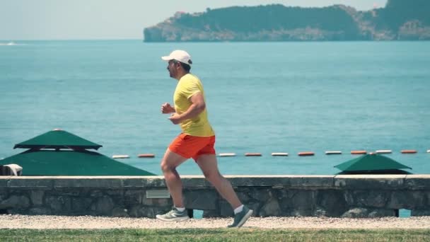 Scatto al rallentatore di un uomo caucasico che corre contro il paesaggio marino — Video Stock