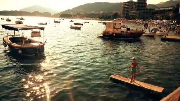 BECICI, MONTENEGRO - 29 de julio de 2018. Niño pescando con una red de mariposas cerca de la playa llena de gente — Vídeos de Stock