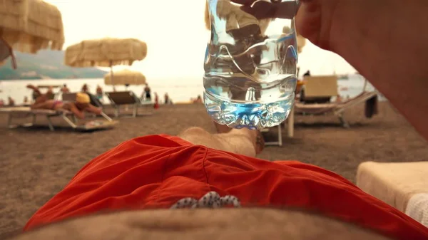 Man drinking water from plastic bottle on the beach — Stock Photo, Image