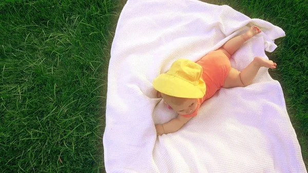 Малыш лежит на полотенце на траве, сверху вниз вид — стоковое фото