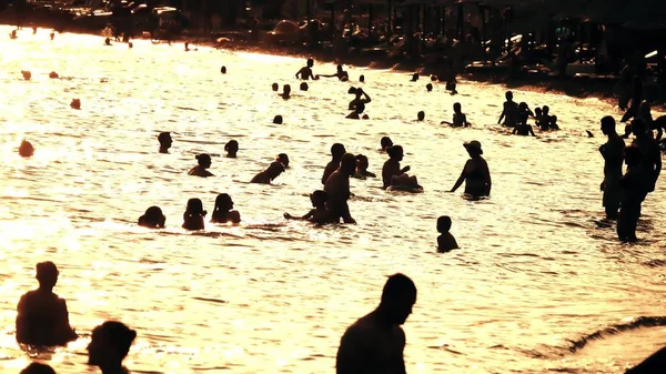 Siluetter av människor på solig strand i solnedgången — Stockfoto