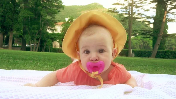 Śmieszne dziecko z różowym smoczka układania na ręcznik na trawie — Zdjęcie stockowe