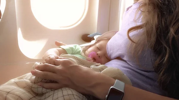 Mamá y su bebé dormido viajando en avión — Foto de Stock
