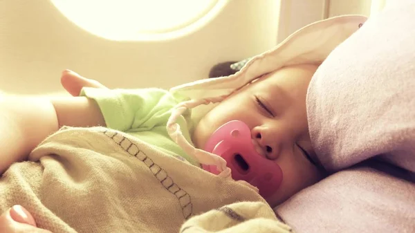 Noworodek śpi z smoczka podczas podróży samolotem — Zdjęcie stockowe