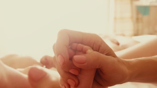 Madre sostiene sus pequeños pies de bebé — Vídeo de stock