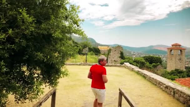 Photographe en t-shirt rouge prend des photos dans le paysage méditerranéen en vacances — Video