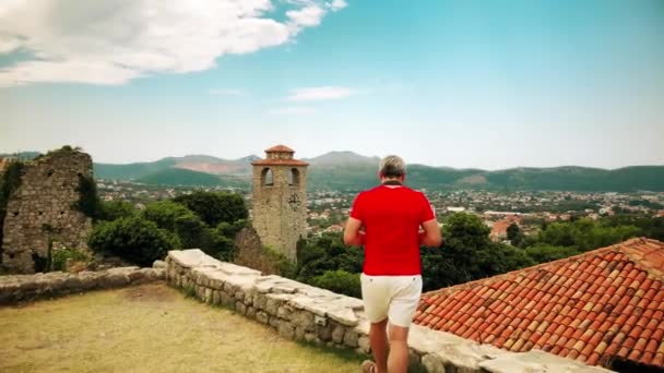 Чоловік у червоній сорочці робить фотографії у відпустці — стокове відео