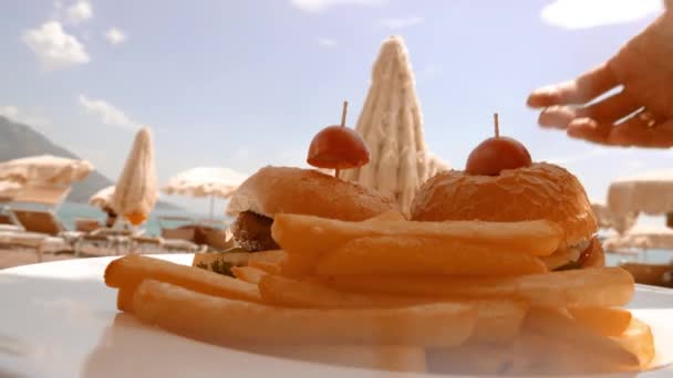 Чоловік і жінка їдять бургерів на пляжі — стокове відео