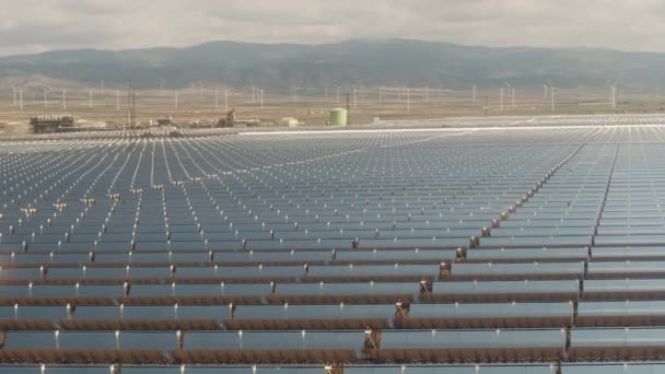 Luftaufnahme von Solarkraftwerken und weit entfernten Windkraftanlagen in niedriger Höhe — Stockvideo