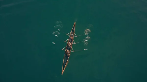 Vista aérea hacia abajo de tres personas desconocidas remando en un barco — Foto de Stock