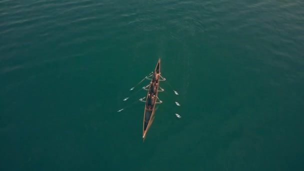 Vue aérienne vers le bas de trois personnes inconnues ramant dans un bateau — Video