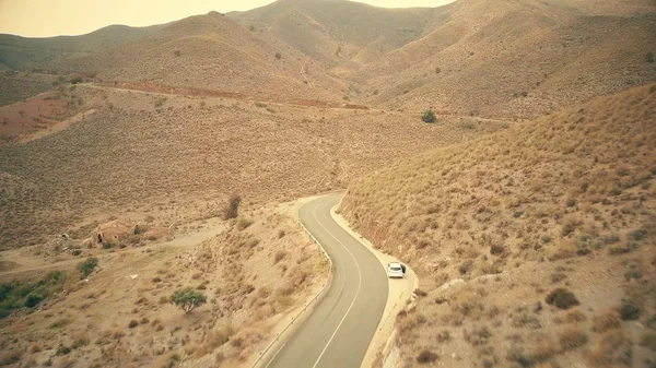 Vista aérea de uma estrada de carro ventoso em montanhas — Fotografia de Stock