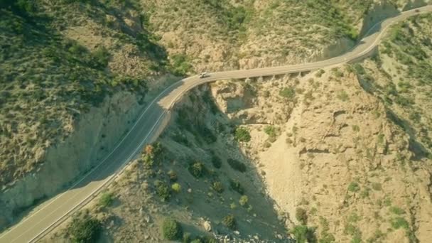 Vista aérea de un coche Guardia Civil moviéndose a lo largo de la carretera ventosa en las montañas andaluzas, España — Vídeos de Stock