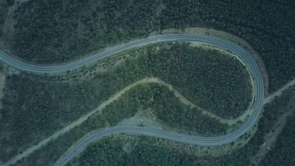Vue aérienne du haut vers le bas d'une voiture blanche stationnée sur une route venteuse dans les montagnes — Video