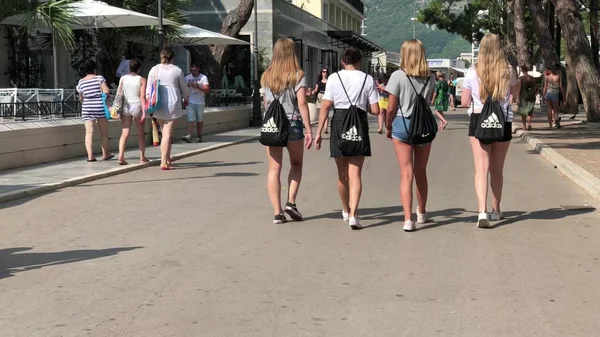 Budva, montenegro - 2. august 2018. junge frauen gehen mit schwarzen nike und adidas rucksäcken die straße entlang — Stockfoto