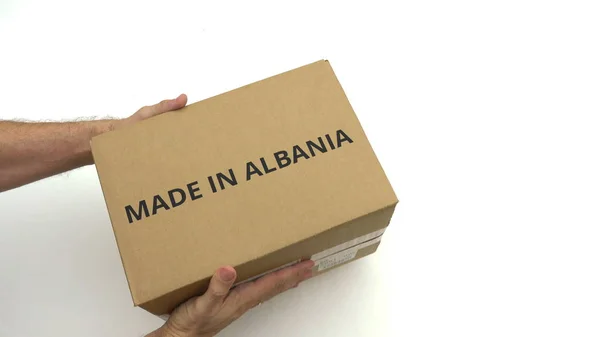 Mãos segurando caixa com texto MADE IN ALBANIA nele — Fotografia de Stock