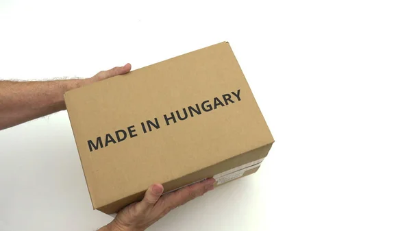 Homem segurando a caixa com MADE IN HUNGARY legenda — Fotografia de Stock